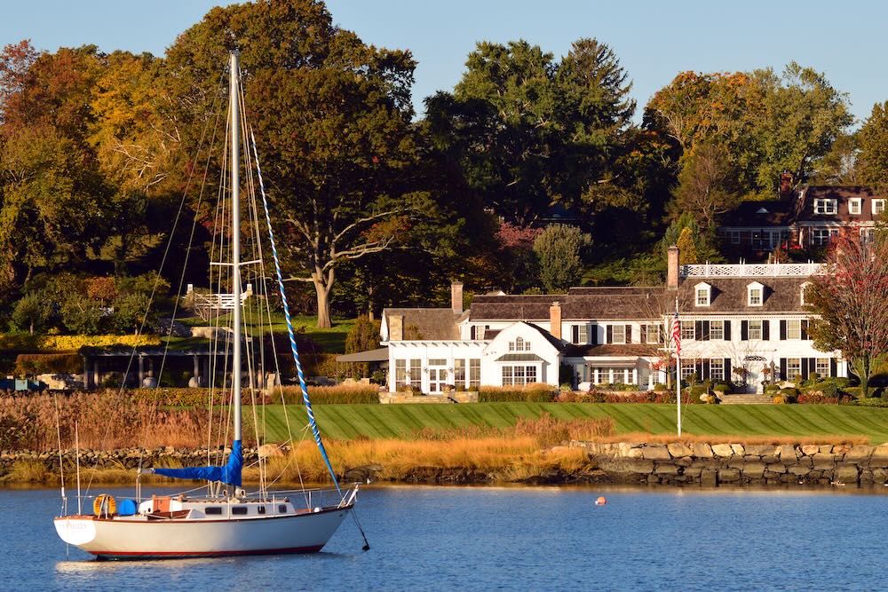 A sailboat is moored at a luxury waterfront homes